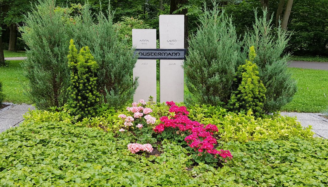 Zweiteiliger Doppelgrabstein aus Kalkstein mit einer modernen Grabbepflanzung aus Bodendeckern  immergrünen Nadelgehölzen und Sommerblumen