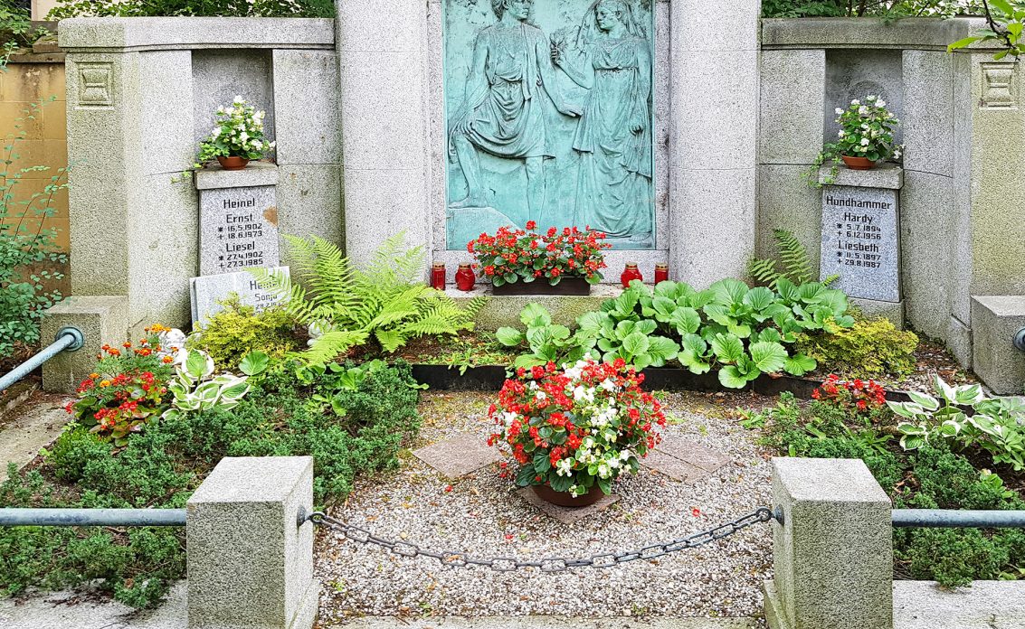 Historisches Familiengrab aus Granit mit einer figürlichen Darstellung auf einer Bronzepl...