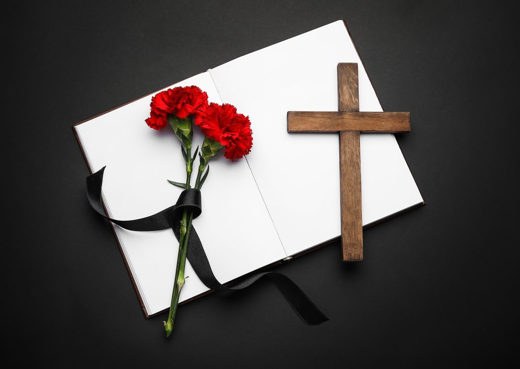 Trauerbuch mit Blumen und Kreuz