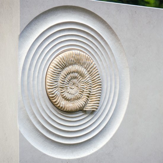 Grabidee für ein Doppelgrab mit Einfassung und Grabstein mit Kalkstein Ammoniten & immergrüner Grabbepflanzung