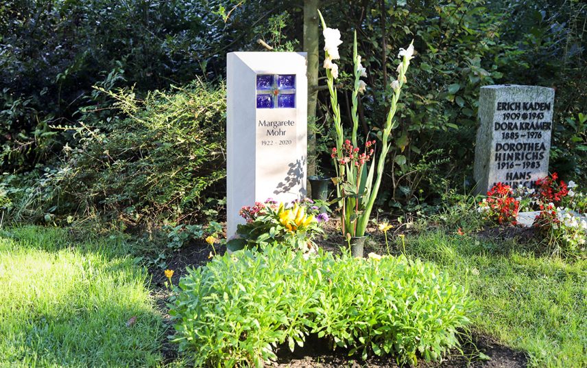 Inspiration für die Gestaltung eines modernen Urnengrabs – Kleines Urnengrabmal aus Kalkstein mit einem blauen Kreuz aus Glas
