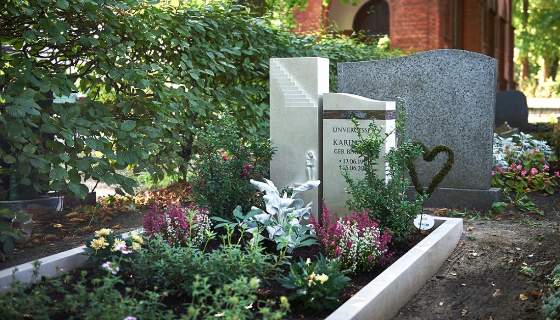 Idee für die Grabgestaltung – Gepflegtes Doppelgrab aus Kalkstein & Bronzeornament – pflegleichte Grabbepflanzung mit Stauden und Gehölzen