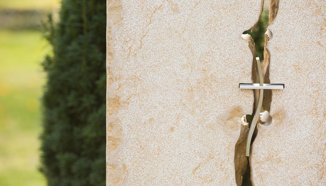 Modernes Doppelgrabmal mit Einfassung aus Kalkstein mit christlichen Symbolen – pflegeleichte Grabgestaltung mit Abdeckplatte  Rindenmulch und Grabgesteck