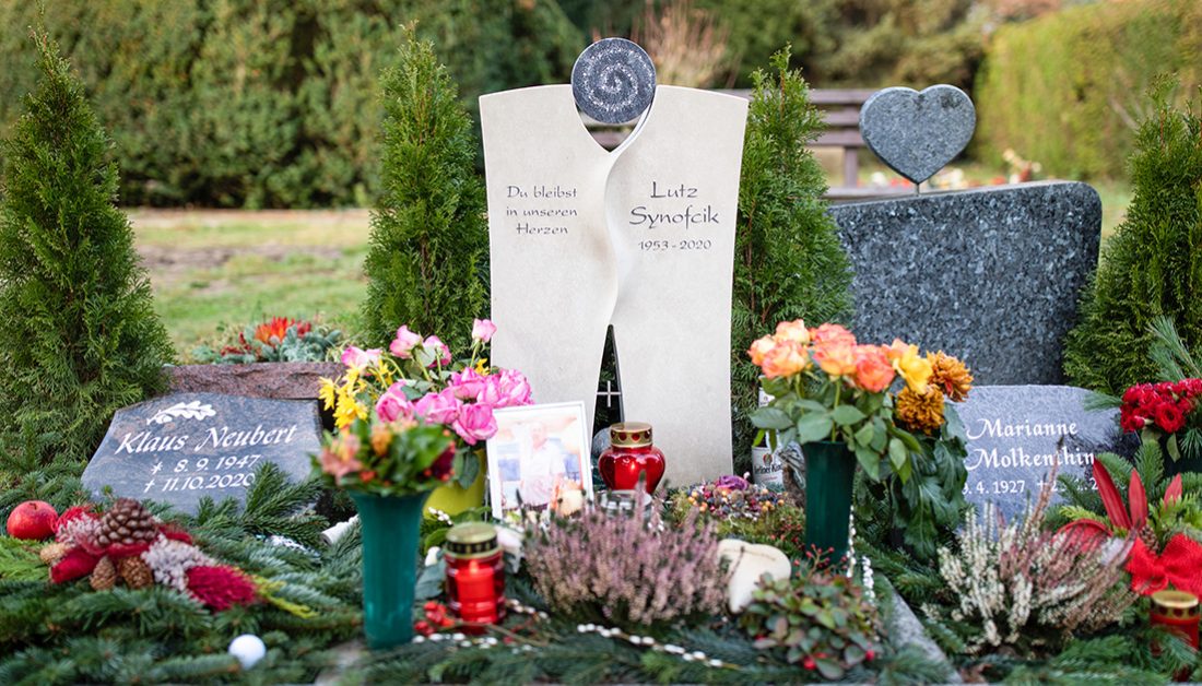 Beispiel Grabgestaltung eines modernen Urnengrabmales aus Kalkstein mit Kristallen – winterliche Grabeindeckung mit Reisig & Blumen