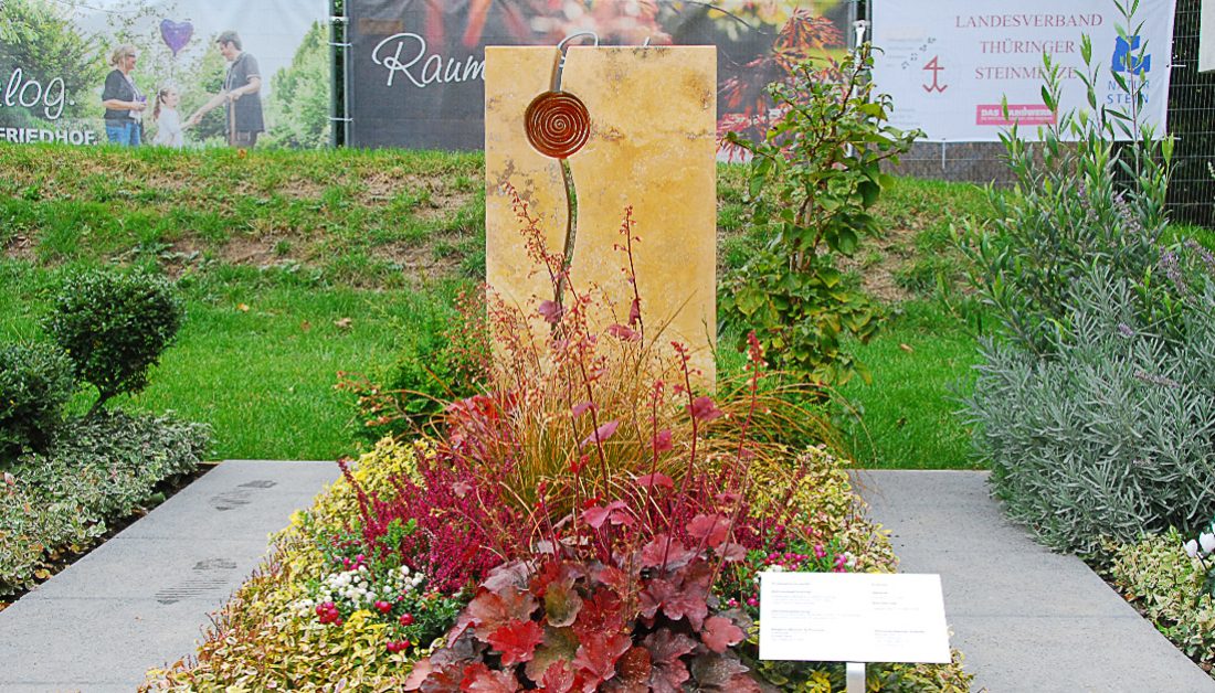geteilter Doppelgrabstein aus Travertin – Lebenslinie & Sonne / üppige Grabbepflanzung für den Herbst in kräftigen Rottönen