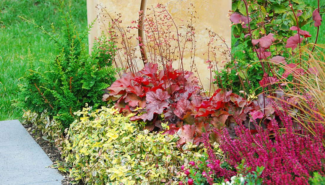 geteilter Doppelgrabstein aus Travertin – Lebenslinie & Sonne / üppige Grabbepflanzung für den Herbst in kräftigen Rottönen