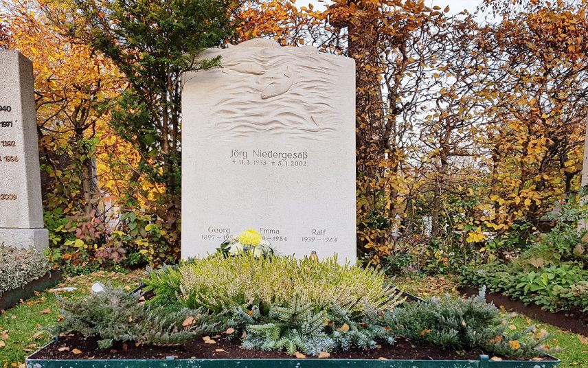 Großer Familiengrabstein aus hellem Kalkstein – Motiv Wasser & Fische / winterliche Grabgestaltung mit Tannengrün und Heidekraut