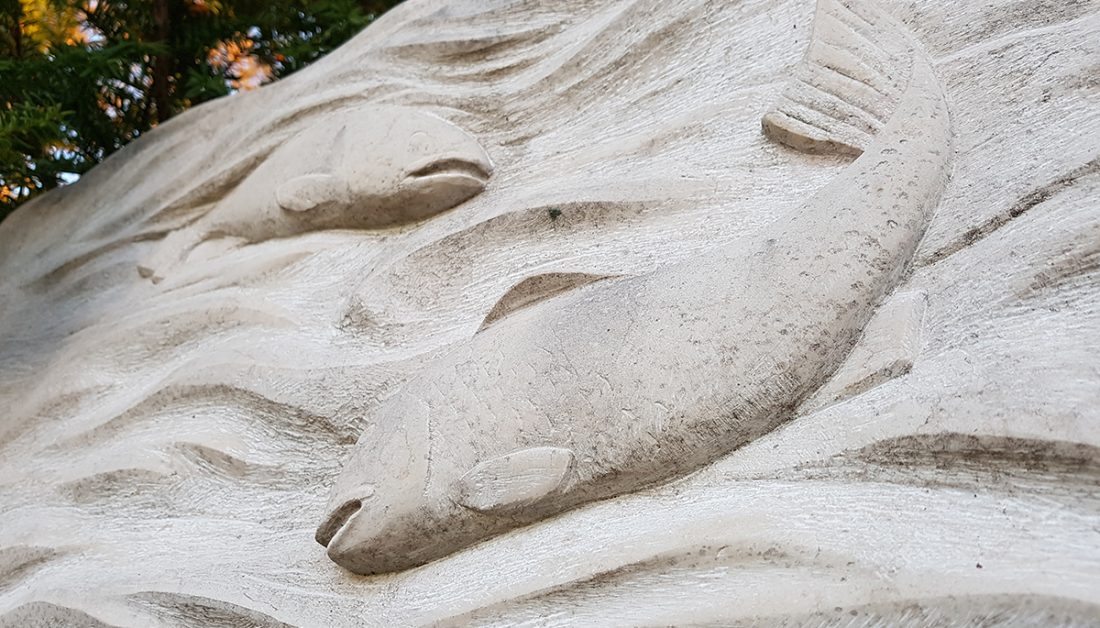 Großer Doppelgrabstein aus hellem Kalkstein - Motiv Wasser & Fische / winterliche Grabgestaltung mit Tannengrün und Heidekraut