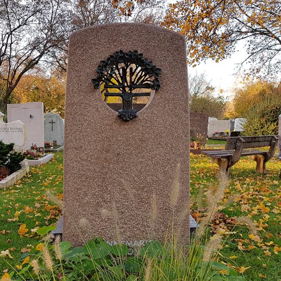 Moderner Grabstein mit Einfassung aus rotem Granit auf einem Urnengrab mit Loch und Bronzeplastik - Sommerliche Grabbepflanzung und Grabschmuck