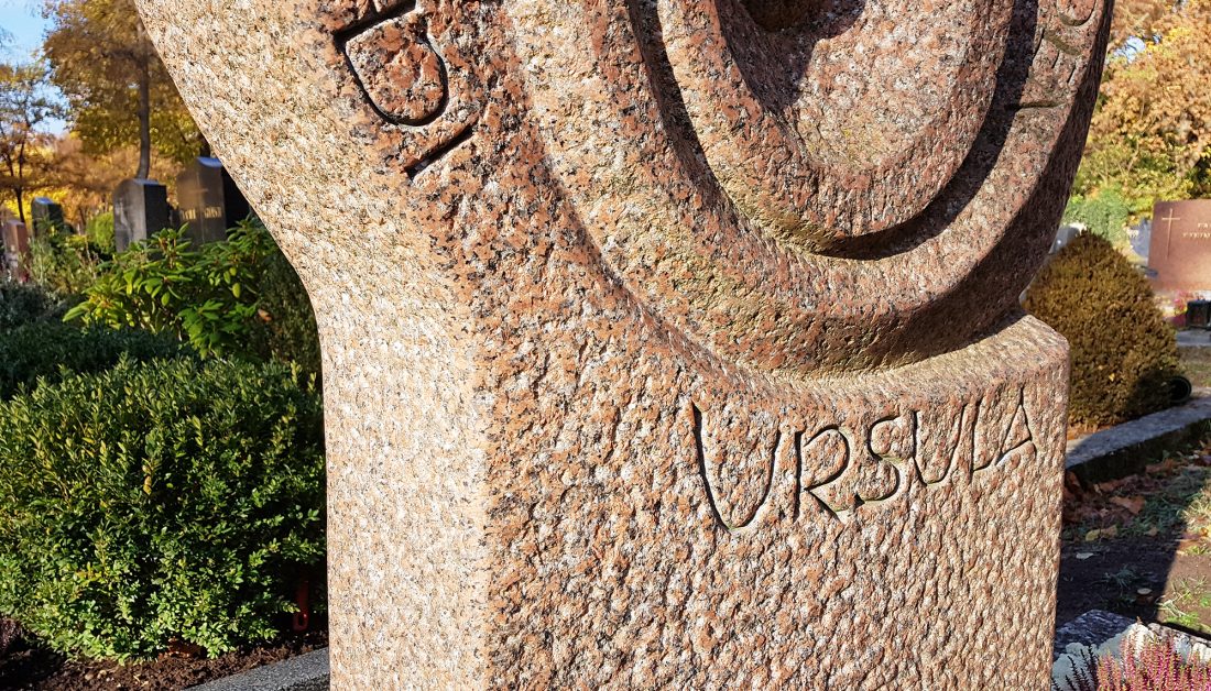 Familiengrab modernes Gestaltungsbeispiel – runder Grabstein  Abdeckplatten und Einfassung aus rotem Granit / winterlicher Grabschmuck mit Heidekraut  Islandisch Moos und Tannengrün