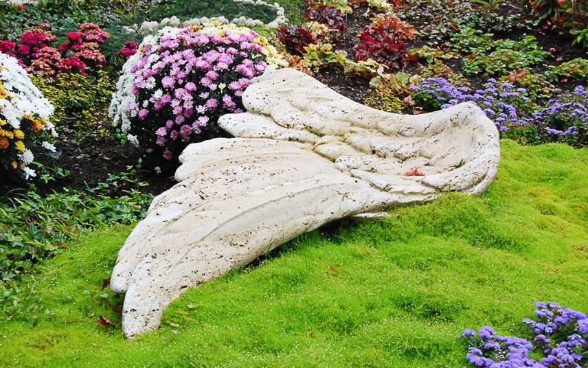 Asymetrische Grabbepflanzung eines modernen Einzelgrabes aus schwarzem Granit mit pflegeleichten Bodendeckern und Sommerblumen