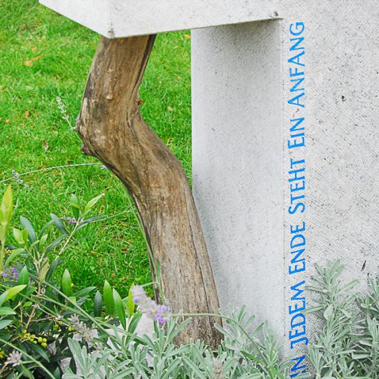 Modernes Grabmal aus Kalkstein mit einem Holzzweig - Grabbepflanzung Inspiration saisonal mit Strukturgehölzen