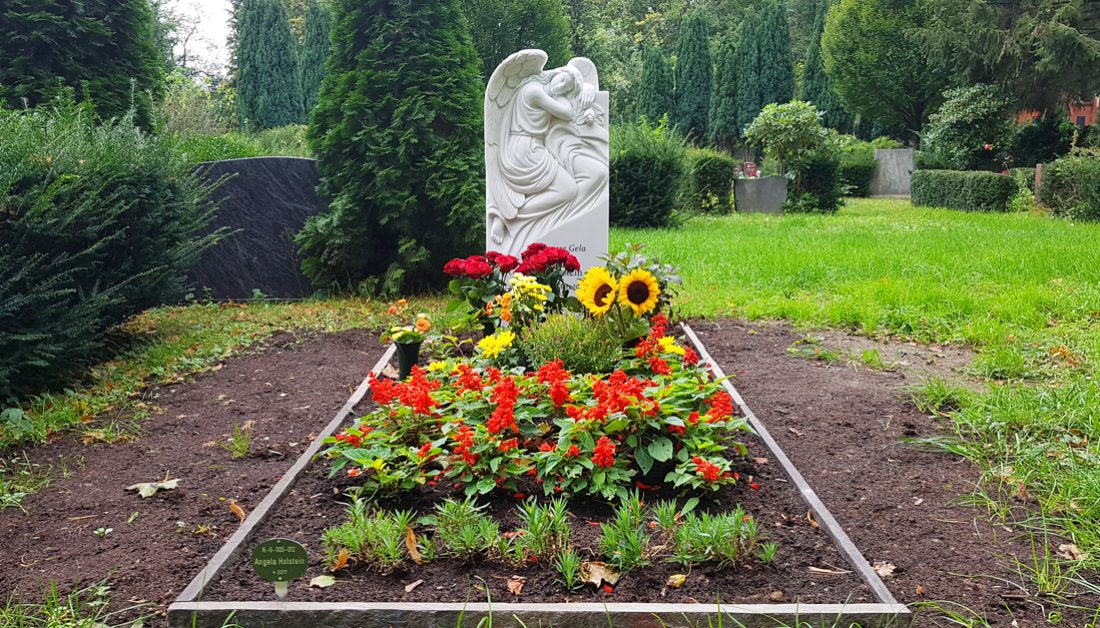 Klassisches Grabmal mit Engel aus Marmor für ein Einzelgrab / Grabgestaltung mit Blumensträußen und blühenden Stauden