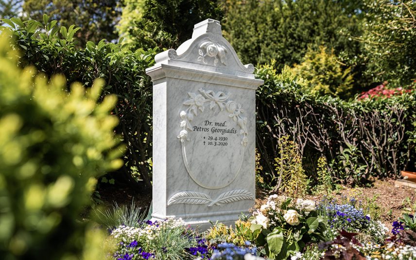 Klassischer Doppelgrabstein aus weißem Marmor mit floralen Details – Gestaltung der Grabstätte mit Frühjahrsbepflanzung