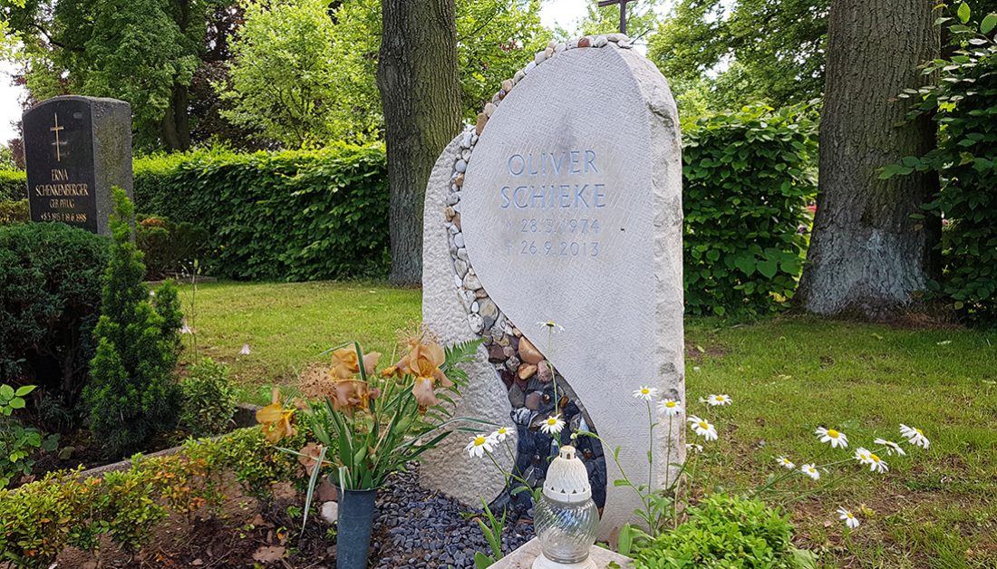 Heller Grabstein aus Kalkstein mit einem Band aus Kieselsteinen & einem Kreuz – Grabgestaltung mit einer Einfassung aus Buchsbaum und robusten Sommerblumen