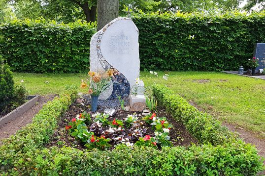Heller Grabstein aus Kalkstein mit einem Band aus Kieselsteinen & einem Kreuz – Grabgestaltung mit einer Einfassung aus Buchsbaum und robusten Sommerblumen