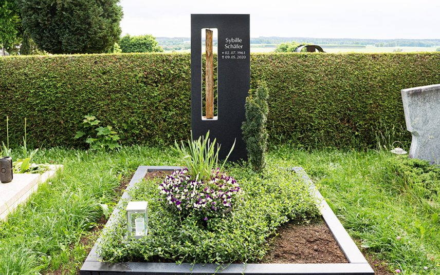 Klassische Doppelgrabanlage mit einem schmiedeeisernen Grabkreuz und Bronzetafeln – Grabgestaltung mit Solitärgehölzen und Bodendeckern