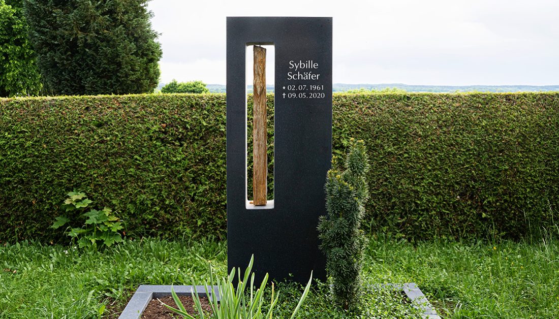Doppelgrab mit modernem Grabstein aus schwarzem Granit & Treibholz - pflegeleichte Grabbepflanzung mit Immergrün und Nadelgehölz