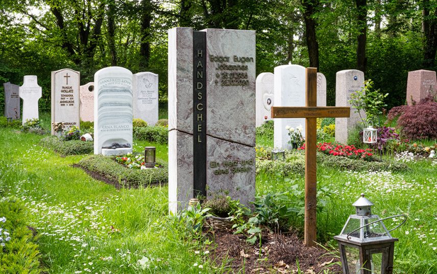 Doppelgrab mit modernem Grabstein aus schwarzem Granit & Treibholz – pflegeleichte Grabbepflanzung mit Immergrün und Nadelgehölz