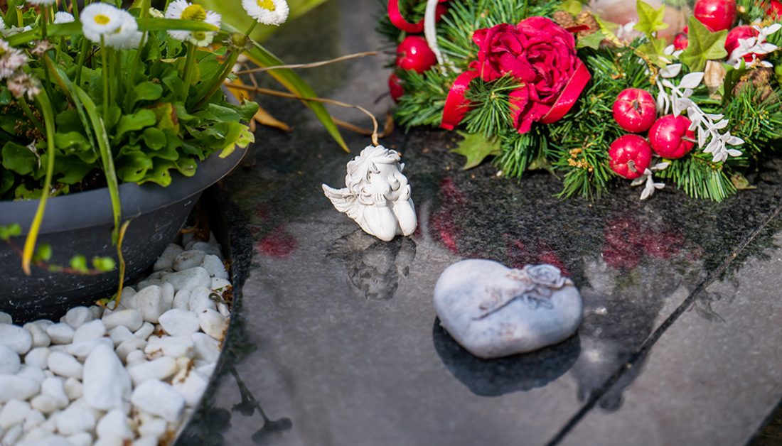 Schönes Urnengrab im Kontrast Schwarz/ Weiß aus einem Marmorgrabstein und einer Graniteinfassung/ Grabgestaltung mit Abdeckplatte  Kies & Blumengesteck