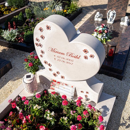 Einzelgrabmal in Herzform aus hellem Kalkstein mit Sockel  Einfassung und Grablaterne - sommerliche Grabbepflanzung mit Blumen