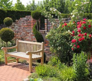 Romantische Gartengestaltung mit Gartenbank aus Holz