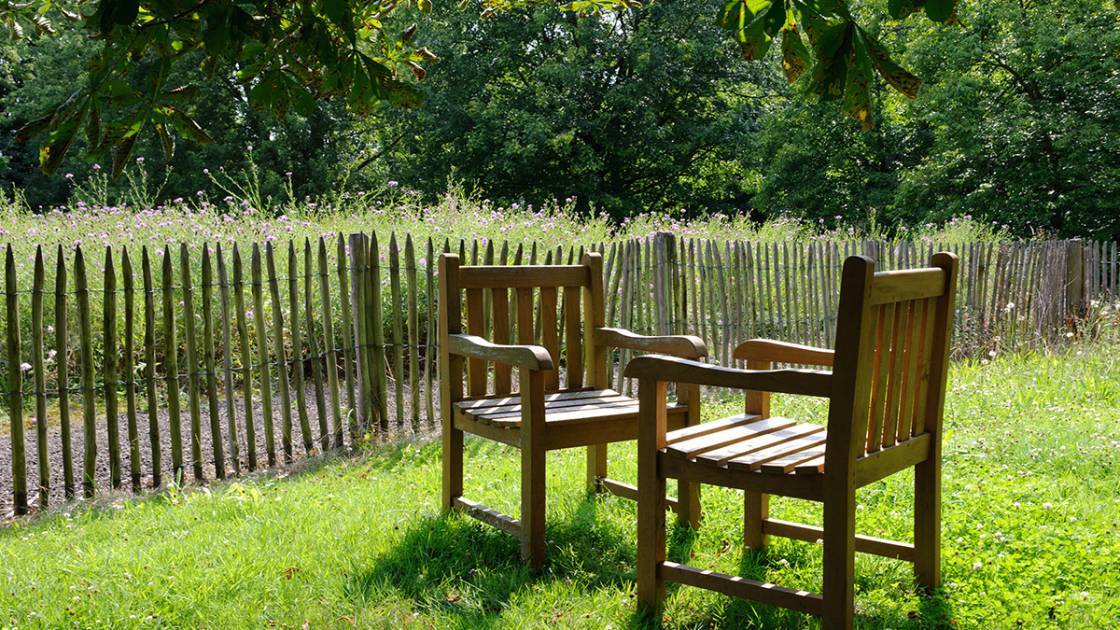 Staketenzaun als Gartenumzäunung mit einem gemütlichen Sitzplätzchen auf dem Rasen