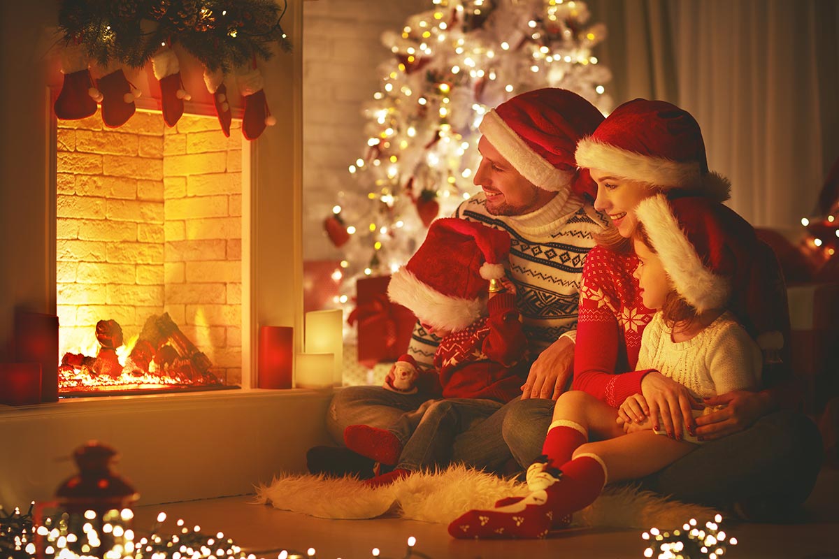 Familie vor weihnachtlichem Kamin und Weihnachtsbaum