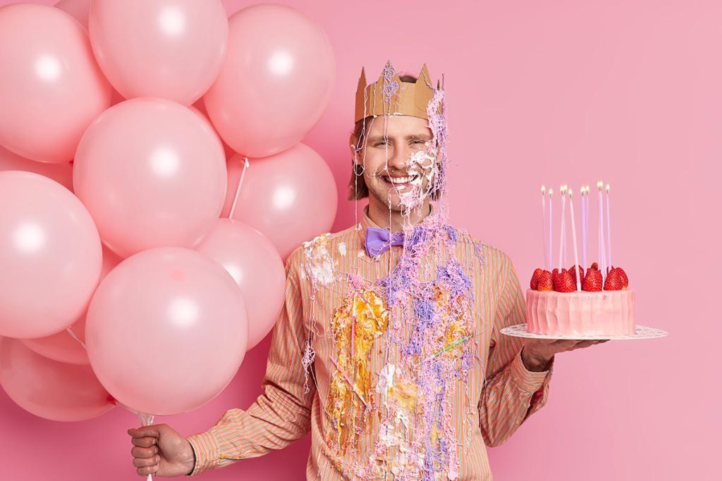 Lustiger Mann feiert Geburtstag mit Ballons und Kuchen