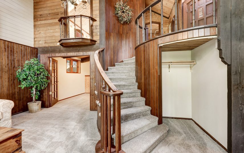Offener Eingangsbereich mit Empore in großem Landhaus aus Holz & verlegter Teppichboden sowie Einbau-Garderobenschrank