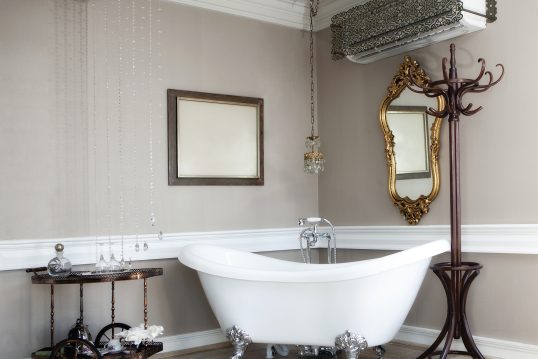 Pompöses Badezimmer mit barocken Stilelementen – freistehende Badewanne mit versilberten Standfü...