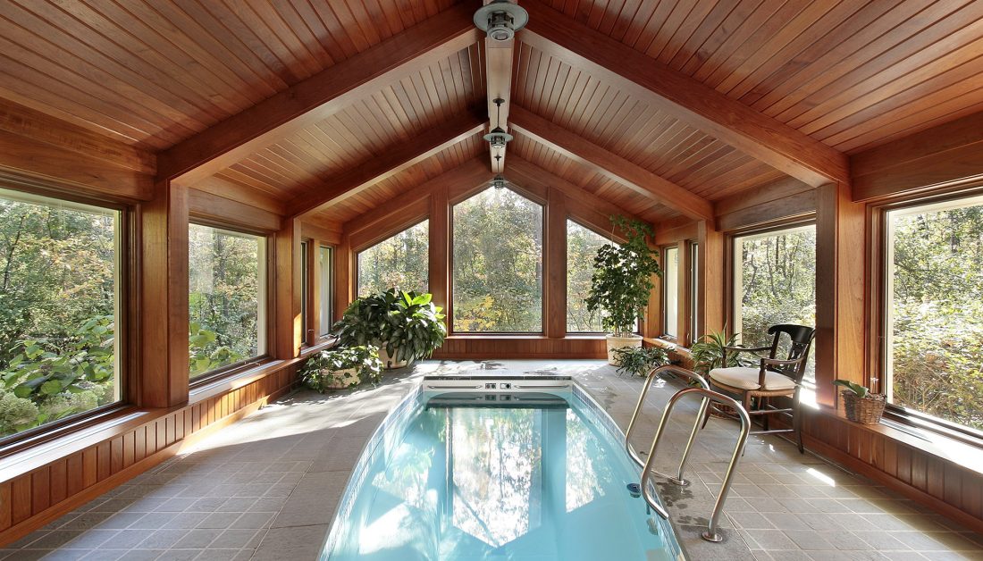 Moderner Innenpool im Dachgeschoß eines Landhauses - GfK Schwimmbecken mit Whirlpoolfunktion - Natursteinboden & Holzvertäfelung