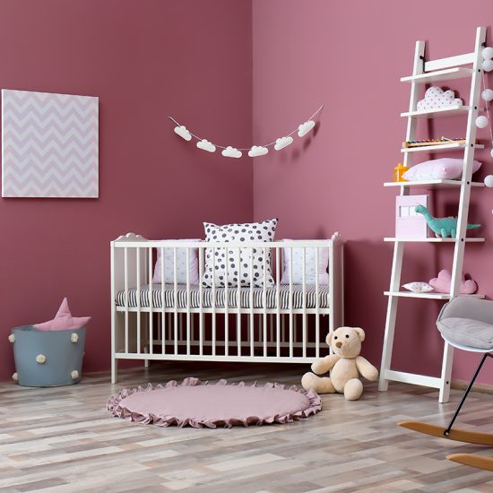Gestaltungsidee für ein Mädchen Babyzimmer mit pinken Wänden - weißes Babybett & weißes Leiterregal - Schaukelstuhl & Beistelltisch - runder Teppich in pink