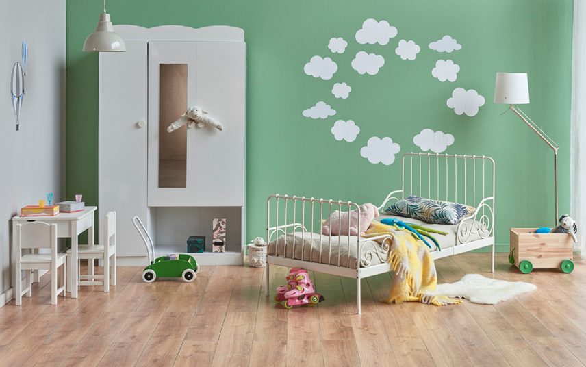 Kinderzimmer für Jungen Gestaltungsidee in grün mit Wolken Wanddekoration – weißes Metallbett & großer Kleiderschrank – Hängelampe & Stehlampe – Kindersitzgruppe mit Stuhl & Tisch