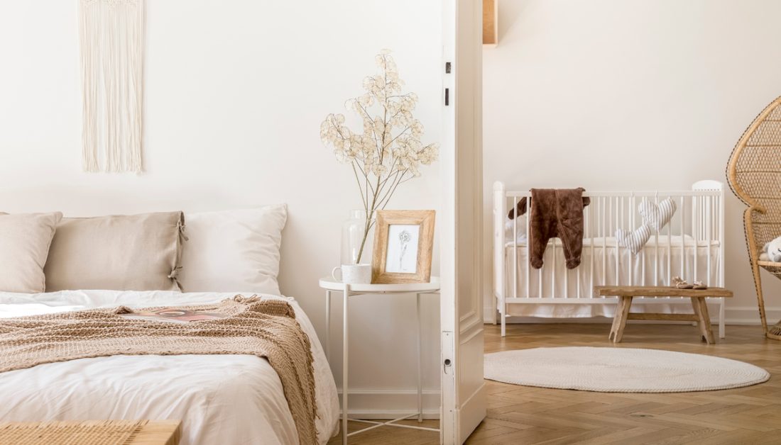 Idee für ein Schlafzimmer mit integriertem Babyzimmer - helle Raumgestaltung im Landhausstil mit Holzfußboden & weißen Möbeln - weißes Babybett & Holzhocker - weißer Metall Beistelltisch neben einem Futonbett - selbstgemachtes Makramee als Wandgestaltung