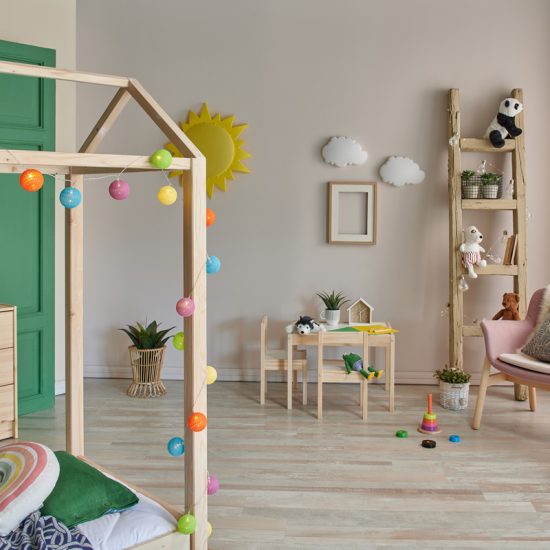 Kinderzimmer Gestaltungsidee für Jungs & Mädchen mit Holzmöbeln - beige & grüne Wandgestaltung - Hausbett aus Holz dekoriert mit Lichterkette & Sitzbereich - Leiterregal als Ablage - Loungestuhl mit rosa Polsterung
