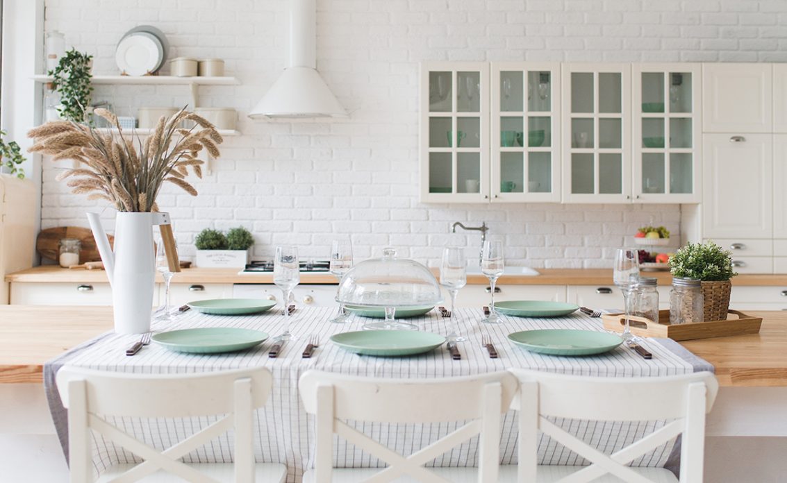Dekorierter Tisch in einer weißen Landhausküche als Wohnidee – Beispiel mit gestreifter Tischdec...