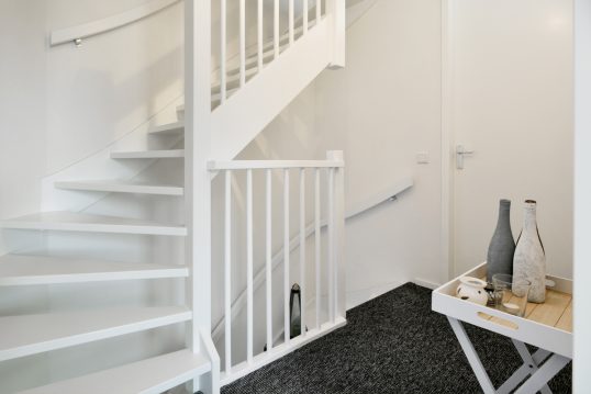 Skandinavische Flurbereich Inspiration im Dachgeschoss mit weißer Treppe – Beispiel mit dekorierten Beistelltisch – Teelicht & Vasen – Auslegwaren Teppich im Treppenhaus