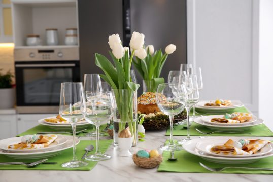 Tischdeko Idee für Ostern – Beispiel mit grünem Tischset auf dem Esstisch  Glasvasen mit Blumen – orange-weiße Servietten