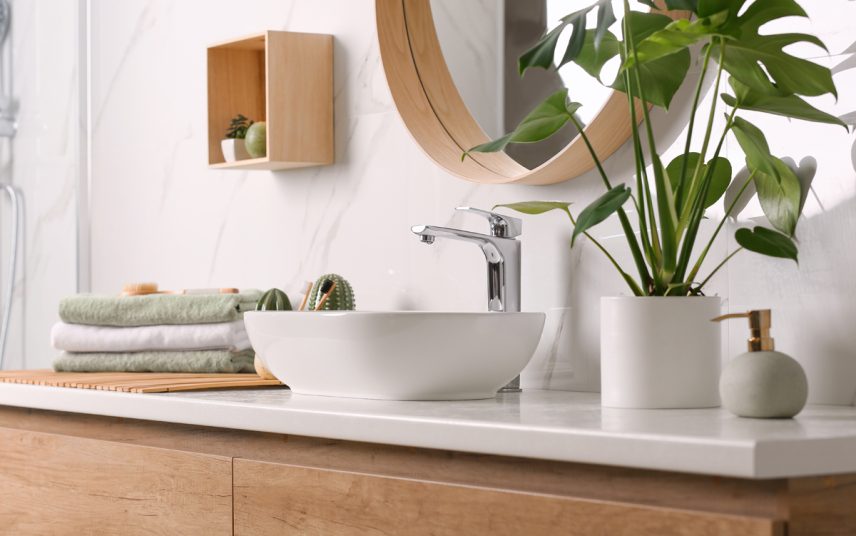 Deko Idee für das Badezimmer – Beispiel mit dekorierten Waschbeckenunterschrank  Zimmerpflanze in Pflanzgefäß & Handtücher – Wandregal & Spiegel mit Holzrahmen
