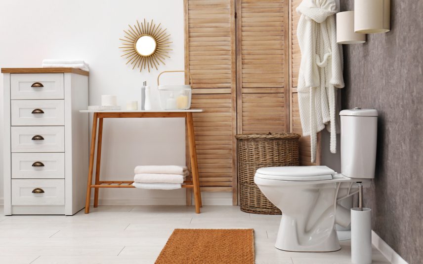 Moderne Einrichtungsidee für das Badezimmer mit Möbeln & Deko – Beispiel mit Ablagetisch & Badschrank – kleiner runder Dekospiegel – Raumteiler & Badteppich