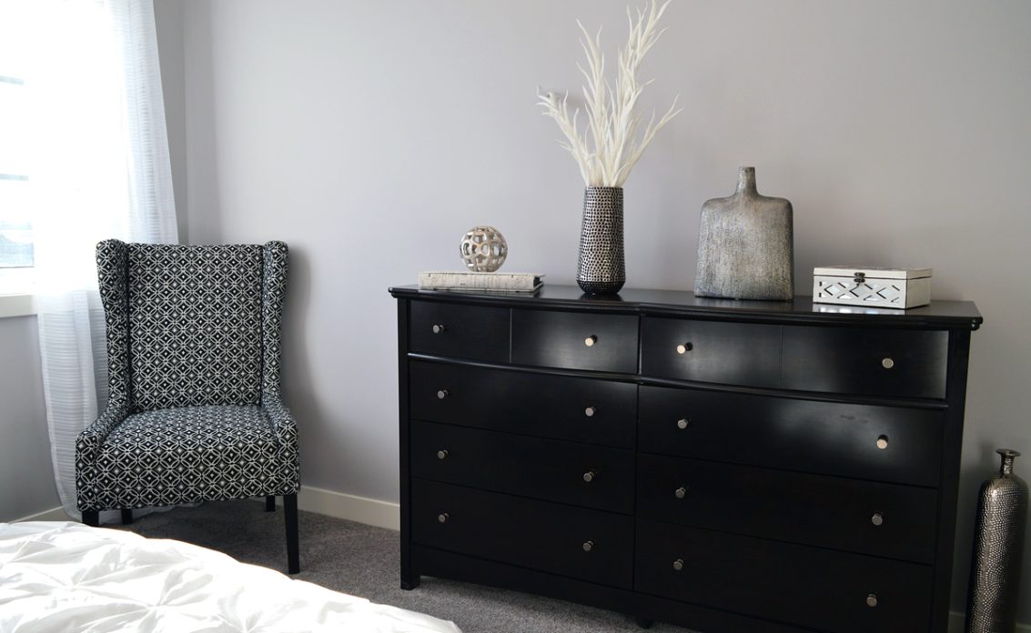 Schlafzimmer Idee mit schwarzer dekorierter Kommode & gemusterter Ohrensessel – Beispiel mit graue...