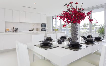 Gestaltungsbeispiel für eine weiße moderne Küche mit schwarz-weißer Tischdekoration – roter Bl...