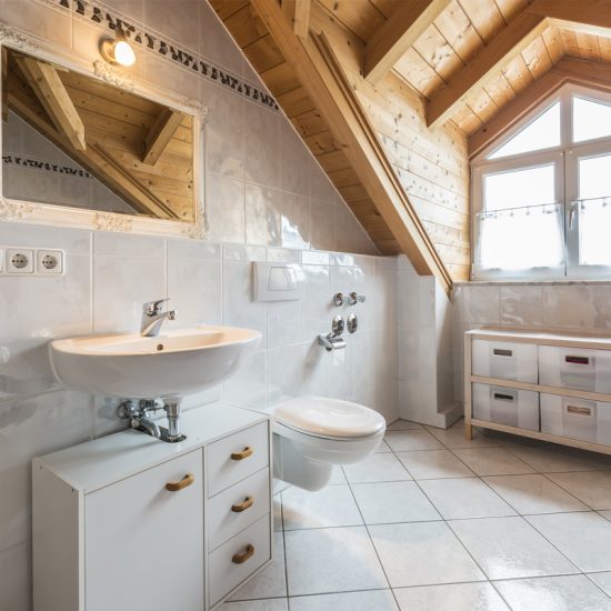 Idee für die Badezimmergestaltung im Landhausstil mit Dachschrägen - Beispiel für ein Bad mit Waschbeckenunterschrank  Badschrank & weißen Spiel - Spiegelleuchte