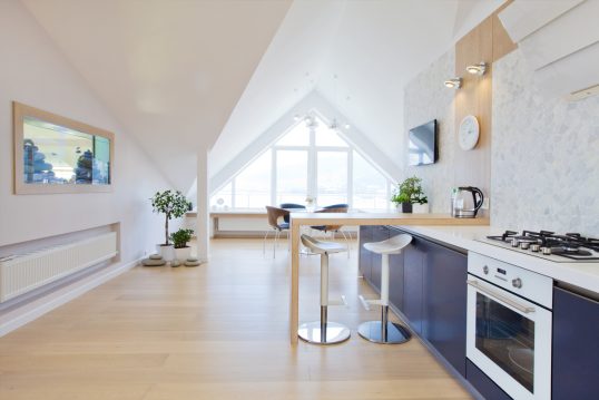 Modernes Dachgeschoss Appartement oder Ferienwohnung Idee – Wohninspiration mit Küchenzeile & Tresentisch – weiße Barhocker – Spiegel an der weißen Wand