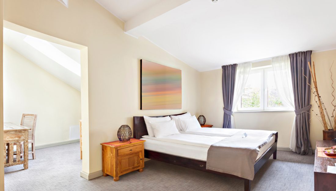 Gestaltungsidee für eine Ferienwohnung auf dem Dachboden - Schlafzimmer Beispiel mit Holzbett  Holznachtschrank mit Kerze & Bild über dem Bett - Vorhänge vor den Fenstern