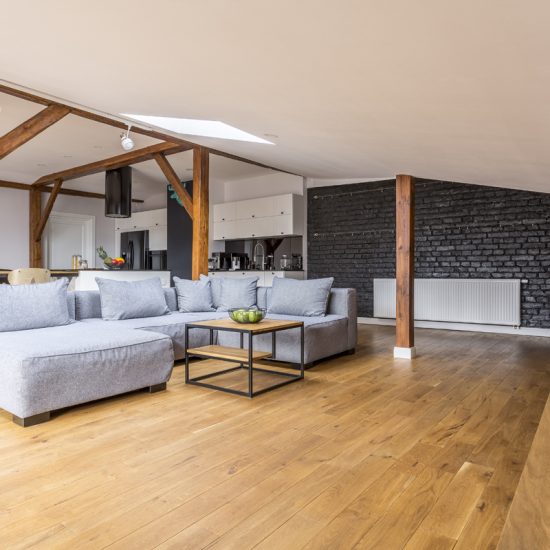Wohnidee - Beispiel für ein geräumiges Wohnzimmer unter dem Dach im klassischen Stil mit grauem Sofa  Couchtisch & schwarzer Ziegelwand - Deckenleiste mit Lampen