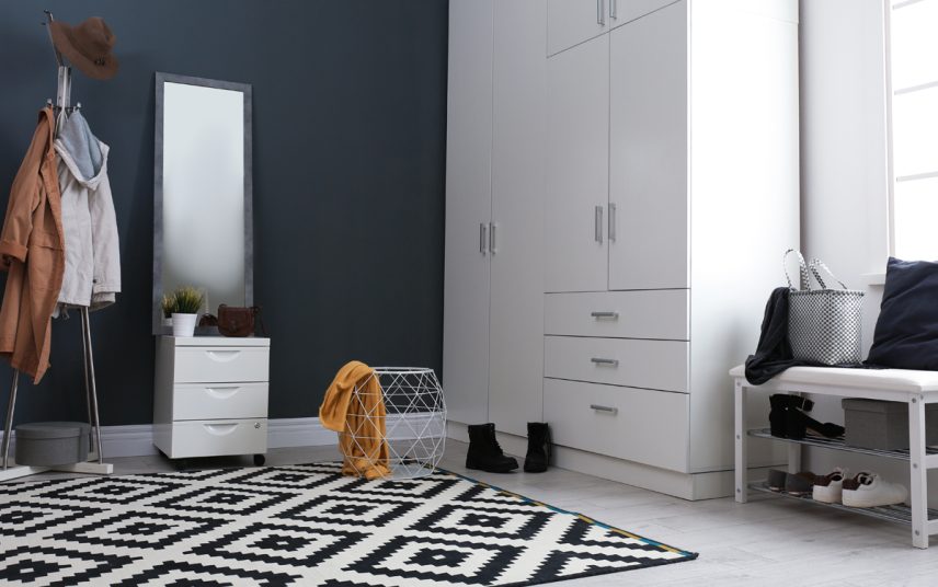 Geräumiger Hausflur mit dunkelblauer Wandfarbe – Beispiel mit großen Schrank im Flur – Spiegel & Garderobenbank für Schuhe – großer Designteppich