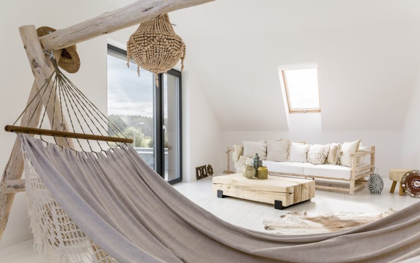 Gestaltungsidee für ein Jugendzimmer im Dach – Boho Style Dachzimmer mit Futonsofa & Holzbeistelltisch mit Dekovasen – Hängematte & Fellteppich