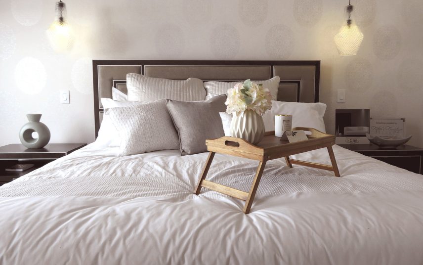 Moderne Deko Idee für das Schlafzimmer – Gestaltungsbeispiel mit Bettisch aus Holz auf dem großen Bett – Nachtschränke mit Vase & Dekoschale – Hängelampen als Schlafzimmerbeleuchtung